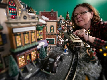 A woman places a trolly in a miniature Christmas village.