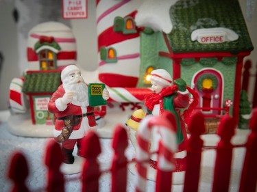 Santa and Mrs. Claus outside a post office in a miniature Christmas village.