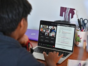 A teenager is shown on a laptop computer attending class via Zoom during the COVID-19 pandemic.