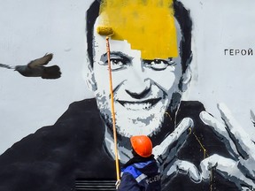 A worker paints over graffiti of jailed Kremlin critic Alexei Navalny in Saint Petersburg on April 28, 2021.