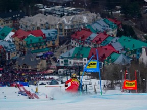 An alpine skier goes down the hill with the coloured houses of Mont-Tremblant in the background