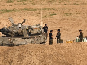 Israeli soldiers stand next to a self-propelled artillery howitzer near the border with the Gaza Strip in southern Israel on Dec. 28, 2023 amid ongoing battles between Israel and the Palestinian militant group Hamas.