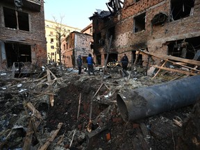 Local residents inspect damage outside an apartment building after the overnight Russian drones attack in Kharkiv, on Sunday, Dec. 31, 2023, amid the Russian invasion of Ukraine.