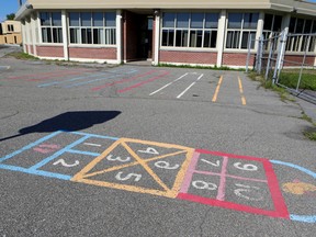 Hopcotch numbers are drawn on the asphalt in a school yard outside a building