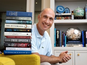 Jonathan Goodman smiles while sitting behind a stack of books