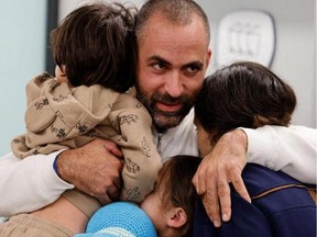 A handout picture released by the spokesperson's office of Schneider Children Medical Center in the Israeli city of Petah Tikva on Nov. 26, 2023 shows Avihai Brodetz hugging his children Ofri (C), Yuval (R), and Oria at the medical facility, after their release by Hamas amid an exchange operation of hostages against Palestinian prisoners.