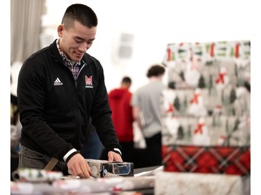 Henry Tung, strength and conditioning coach for the McGill basketball team, volunteers to wrap gifts during the Montreal Community Cares Christmas Gift Wrapping Party, in Montreal, on Sunday, Dec. 3, 2023.
