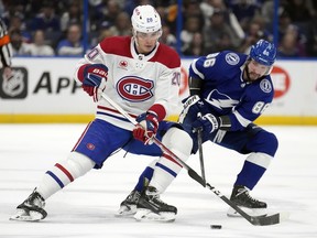 Canadiens' Juraj Slafkovsky (20) and Tampa Bay Lightning forward Nikita Kucherov (86) battle for a loose puck on Sunday, Dec. 31, 2023, in Tampa, Fla.