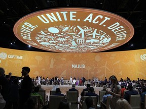 Delegates at the COP28 U.N. Climate Summit sit under a sign that says UNITE, ACT, DELIVER, on Dec. 10, 2023, in Dubai.