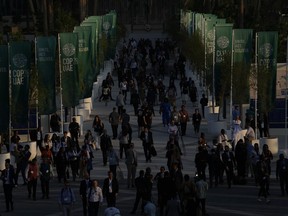 People walk through the COP28 UN Climate Summit as the sun sets, Dec. 2, 2023, in Dubai, United Arab Emirates.