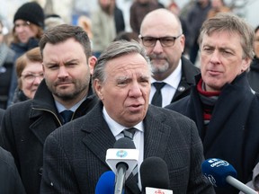 Three Quebec politicians are standing at a microphones for a press conference