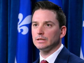Closeup of a man with a Quebec flag behind him.