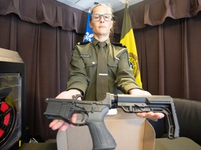 A uniformed police officer displays two guns.