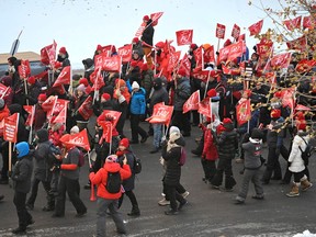 Dozens of people march while holding red flags