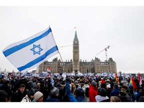 A large Israeli flag is visible above a crowd in front of the Parliament building