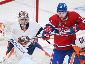 Canadiens' Josh Anderson (17) tries to deflect the puck pass New York Islanders goaltender Semyon Varlamov in Montreal, on Saturday, Dec. 16, 2023.