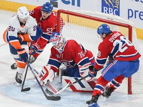 New York Islanders' Hudson Fasching (20) tries to put the puck past Montreal Canadiens goaltender Sam Montembeault as Canadiens' Justin Barron (52) and Christian Dvorak (28) defend in Montreal on Saturday, Dec. 16, 2023.