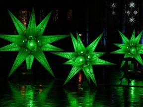 Three large, 3D stars glow green and are reflected in wet pavement.