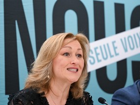 Closeup of a woman at a press conference with a sign behind her that says, "Un seule voix."