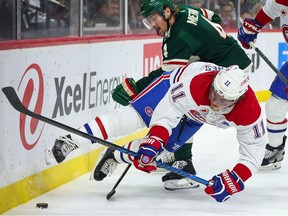 Montreal Canadiens right wing Brendan Gallagher, front, and Minnesota Wild defenseman Jon Merrill (4) compete for the puck as Canadiens center Christian Dvorak (28) defends during the first period of an NHL hockey game Thursday, Dec. 21, 2023, in St Paul, Minn.