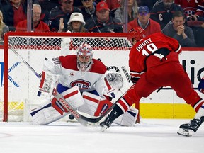 Canadiens goalie Cayden Primeau is seen int eh butterfly position blocking the puck launched at him by Hurricanes' Jack Drury, who is seen from behind facing the goalie.