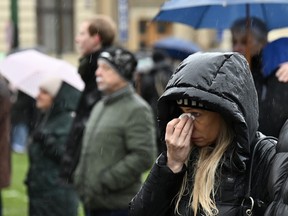 A mourner wipes her eyes in front of the building of Philosophical Faculty of Charles University in downtown Prague, Czech Republic, on Saturday, Dec. 23, 2023.