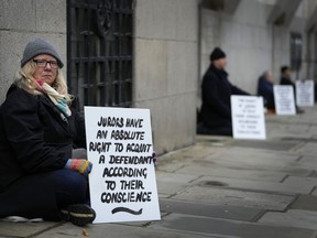Demonstrators hold placards outside The Old Bailey, the Central Criminal Court of England and Wales, in London, Monday, Dec. 4, 2023.