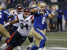An Alouettes player reaches for a Blue Bombers player running with the ball
