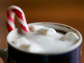 Photo shows a cup of hot chocolate with marshmallows and a candy cane in it.