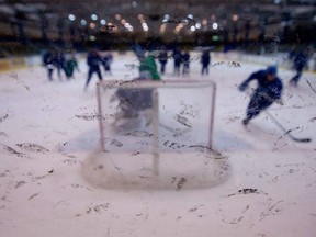 People play hockey, seen blurrily through glass.