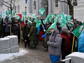 People carry green union flags outside a National Assembly building