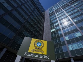 A Surete du Quebec sign is seen in the foreground with two large, windowed buildings in the background.