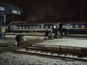 People carry their luggage before boarding an evacuation train in Sumy, Ukraine, Thursday, Nov. 23, 2023.