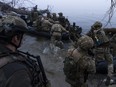 Ukrainian servicemen board a boat on the shore of Dnipro River