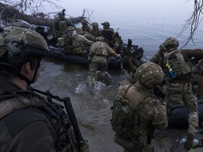 Ukrainian servicemen board a boat on the shore of Dnipro River