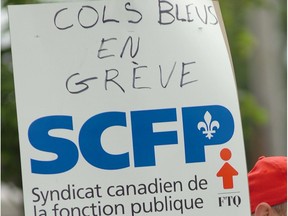 A sign with the SCFP (CUPE) logo has 'Cols bleus en grève' written on it
