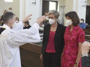 Vicar Wolfgang Rothe, left, blesses couple Christine Walter, centre, and Almut Muenster, right, during a Catholic service.