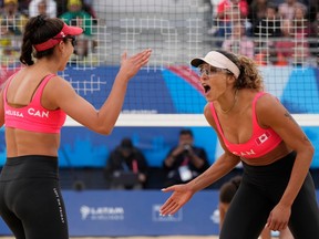 Two women celebrate next to a volleyball net.