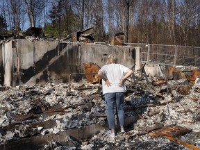 Maureen McGee searches for belongings in the ruins of her family's home after it was destroyed in a wildfire.