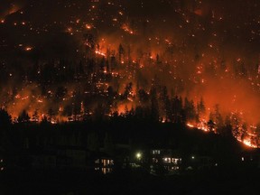 The McDougall Creek wildfire burns on the mountainside above houses in West Kelowna, British Columbia, on Aug. 18, 2023. Canada's first-ever climate adaptation strategy was little more than six weeks old when fast-moving wildfires swept through communities in British Columbia's southern Interior, forcing thousands to flee and destroying several hundred homes.