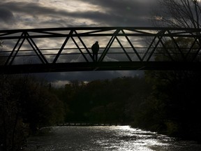 A person walks across a pedestrian bridge over the Credit River in Mississauga, Ont., on Nov. 15, 2021.