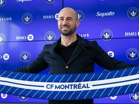 Laurent Courtois holds a CF Montréal scarf in front of him as he poses for pictures