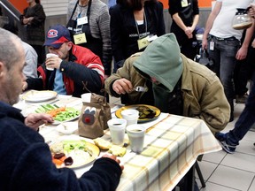 People in winter clothing eat meals at a table