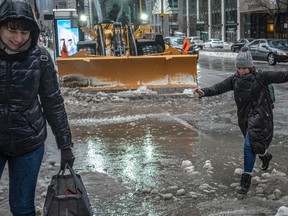A woman jumps over a huge slush puddle. There is a snowplow in the background.