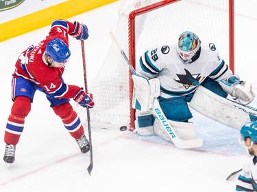 The puck is beside the net between Canadiens' Nick Suzuki and Sharks' Mackenzie Blackwood