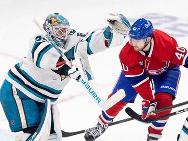 San Jose Sharks' Mackenzie Blackwood leans forward with the puck in his raised glove next to Canadiens' Joel Armia