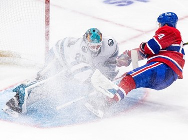 Canadiens' Nick Suzuki slides feet first into San Jose Sharks goalie Mackenzie Blackwood, kicking up a cloud of snow