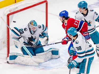 Montreal Canadiens' Josh Anderson and San Jose Sharks' Mario Ferraro, bottom, and Henry Thrun watch the puck bounce off the goal post behind goalie Mackenzie Blackwood