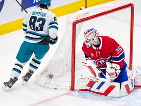 Montreal Canadiens' Sam Montembeault looks back at the puck in the net as San Jose Sharks' Nikita Okhotiuk skates behind the net