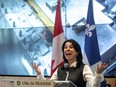 Montreal mayor valerie plante is seen gesturing in front of a photo of a building and flags.